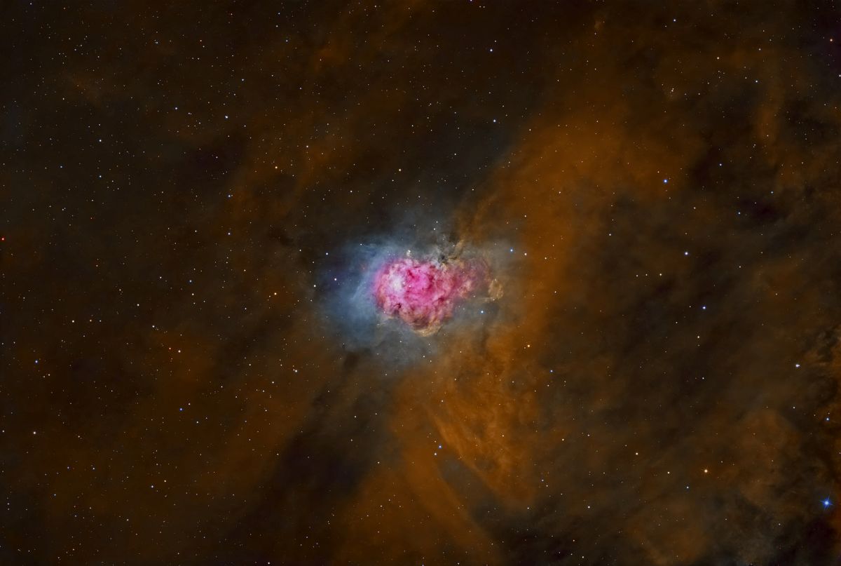 NGC_7358 immersed in a large gas field is a small pink and blue glowing curcular structure.