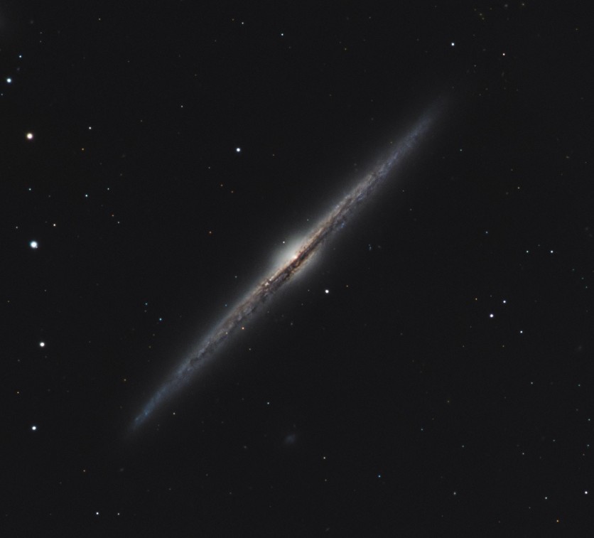 The Needle Galaxy (NGC 4565), an edge-on spiral galaxy showing a thin, bright central bulge with a sharp, elongated dust lane running along its length.