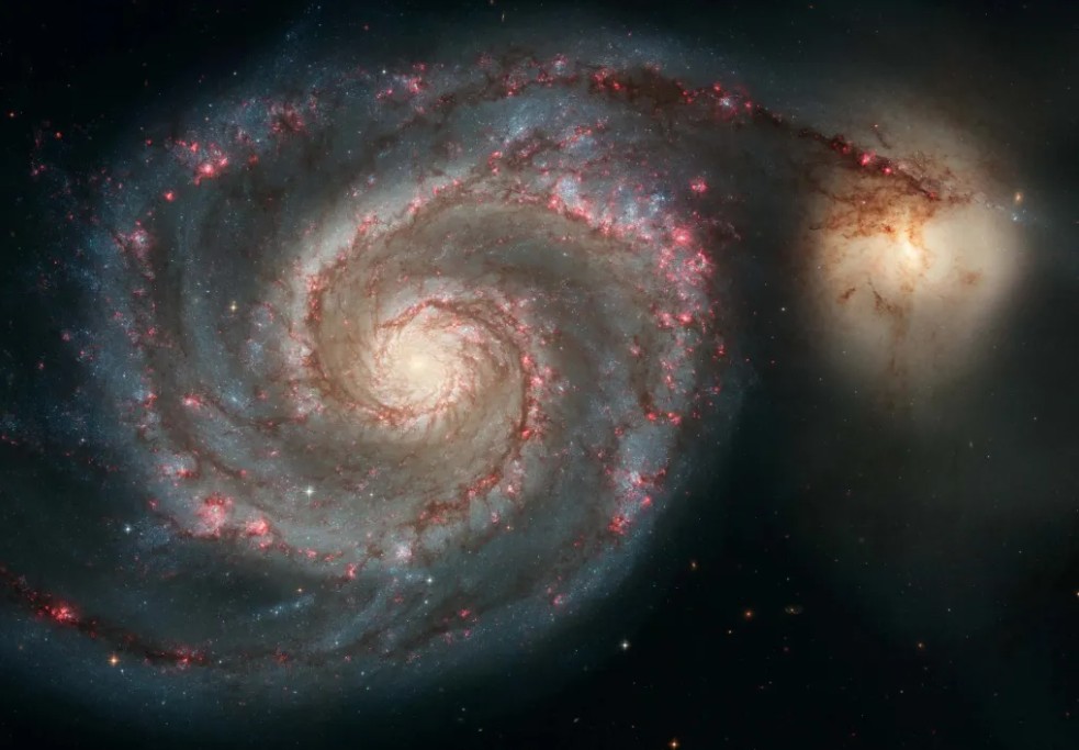 The Whirlpool Galaxy (M51), a classic face-on spiral galaxy with bright, well-defined spiral arms wrapped around a glowing core, interacting with a smaller companion galaxy, creating a stunning cosmic dance captured in vivid detail.
